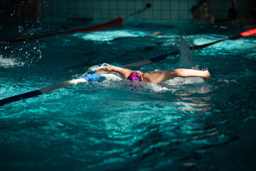 Swimmer swims butterfly swimming style in the pool in beautiful sunlight