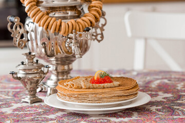 Russian traditions. Russian holiday Maslenitsa. Still life with a stack of pancakes, red caviar, lemon and samovars.