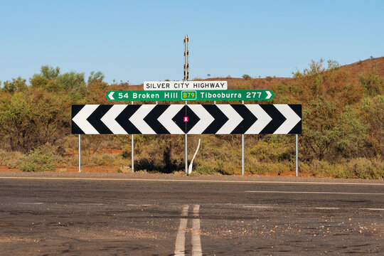 An outback T intersection with a graphic sign showing distances and directions