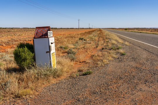 A refrigerator converted into a mailbox on the side of an outback road with power lines