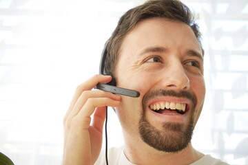 Happy customer service employee is answering to a call using headset. 