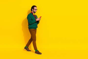Fototapeta na wymiar Full size profile photo of positive person walk use telephone empty space isolated on yellow color background