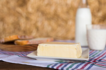 butter, dairy products and bread on the table against the background of hay