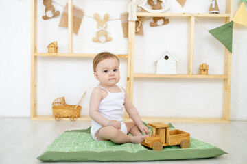 little baby at home in the children's bright room playing with wooden toys, the child at home playing with a typewriter