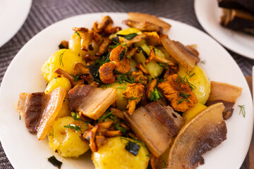baked potatoes with chanterelles and bacon served with herbs on white plate