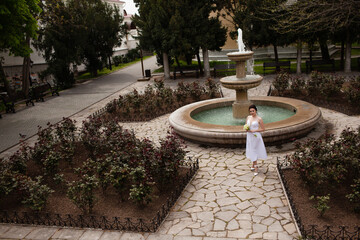 Obraz premium Beautiful bride in a graceful wedding dress, makeup and professional hairstyle posing outdoor