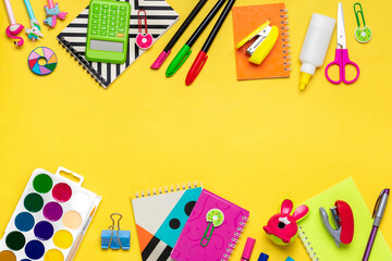 Back to school, education concept. Yellow backpack with school supplies - notebook, pens, ruler, calculator, scissors isolated on yellow background