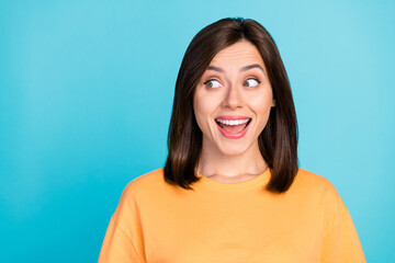 Portrait of adorable impressed astonished girl with long hairdo dressed yellow t-shirt look empty space isolated on blue color background