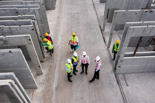 Aerial Top View Of Architect And Engineer Discussing Building Plan At Construction Building Site In Warehouse Factory. Precast Concrete Manufacturing Products On Prefabricated House Factory	