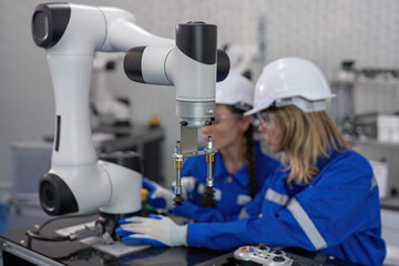 Female senior robotic engineer in modern factory teach new comer operate and maintenance robot arm