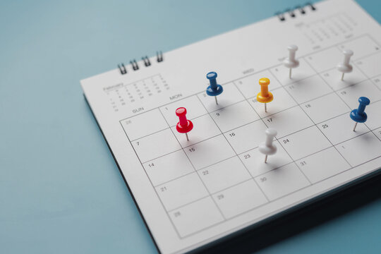 Embroidered red pins on a calendar event Planner calendar,clock to set timetable organize schedule,planning for business meeting or travel planning concept.