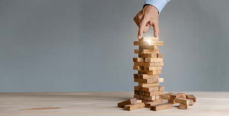 Planning,risk and strategy in business, businessman placing wooden block on a tower.