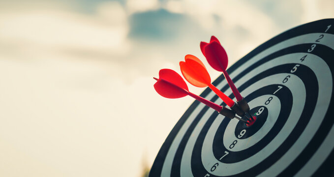 Close up shot of the dart arrow hit on bulleyes of dartboard to represent that the business reached the target  with dark tone picture style. Target and goal as concept.