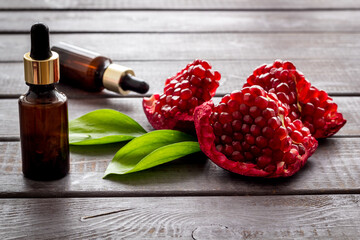 Bottle of pomegranate seed oil with fresh fruits. Natural cosmetic and treatment product
