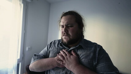 One overweight man having chest pains. A male caucasian person suffering from heart pressure indoors