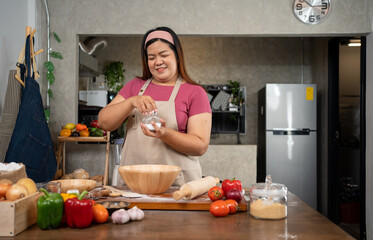 Portrait of obese woman cooking pizza in the kitchen, Raw pizza in the hands of a housewife....
