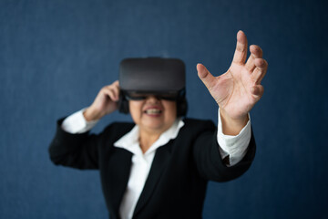 Senior Business woman wearing smart virtual glassest for Video conference, VR  headset glasses technology in modern offices and posing finger pointing and touching. Metaverse concept.