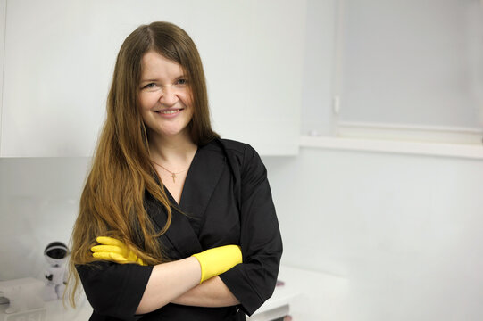 beautiful young woman in yellow latex gloves with flowing hair and in a black bathrobe on a white background Chef hands. Kitchen hygiene. Woman wearing black latex gloves isolated on light