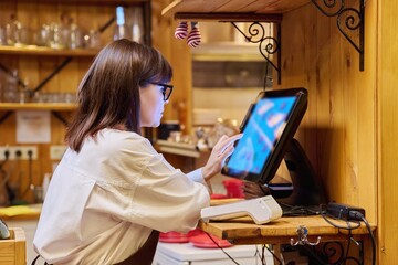 Female restaurant worker using computer terminal while serving customers