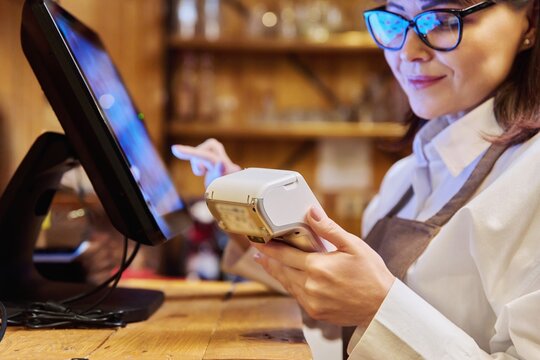 Woman worker manager of restaurant holding wireless banuov payment terminal
