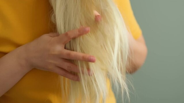 bad effects of bleaching concept. Blonde woman looking at her damaged, split hair. Unhealthy ends of hair extensions. Haircare and hairstyling