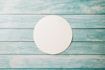 Top view blank round white paper isolated on blue wooden background, abstract geometric shapes,...