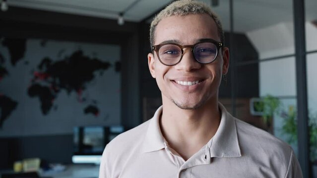Cheerful man with piercing and dyed blond hair looking at the camera in the office