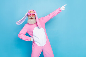 Photo of funky positive man dressed pink rabbit costume sunglass directing empty space hand on...