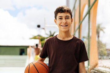 Portrait of a boy with a basketball on a basketball court. The concept of a sports lifestyle,...