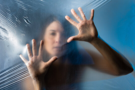Woman touching plastic film while standing behind it