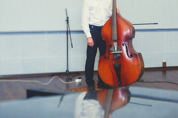 Contrabass cellist player in headphones during rehearsal, recording sound for new album song at...