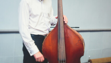 Contrabass cellist player in headphones during rehearsal, recording sound for new album song at...
