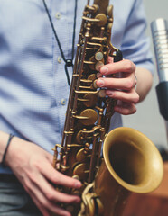 View of a saxophone player in headphones during rehearsal, recording sound for new album song at...