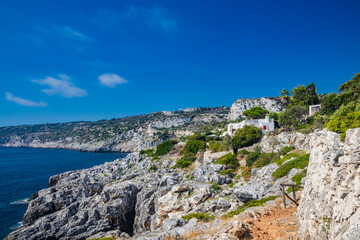 Fototapeta na wymiar Gagliano del Capo. The beautiful panorama on the blue sea, from the rocky cliff of Salento. The nature trail that leads from the Ciolo bridge to the spectacular Cipolliane caves. Sunny day in summer.