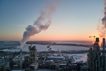 Aerial view of cement factory tower with high concrete plant structure at industrial production area at sunset. Manufacturing and global industry concept