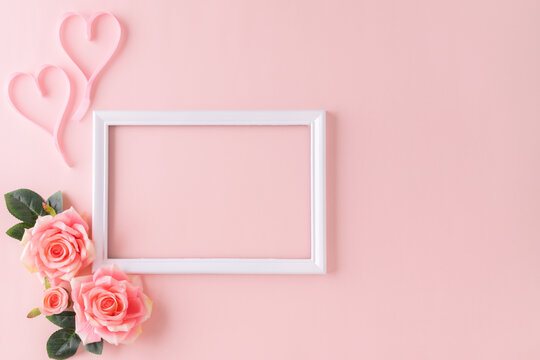 Happy Women's Day decoration concept made from rose flower and pink heart place around frame picture on pastel background.
