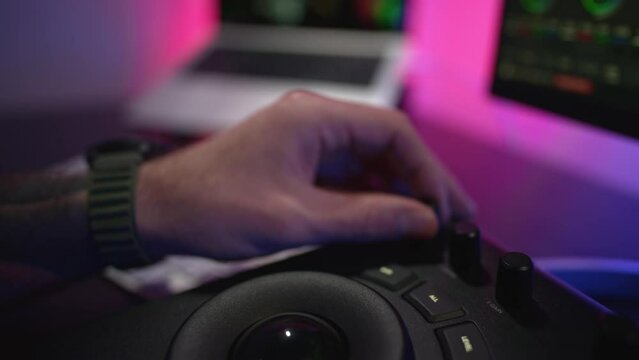 Close-up of a man's hand making edits on a special panel. Young man in glasses working on video editing on computer doing montage and color correction. Concept of creating video content.