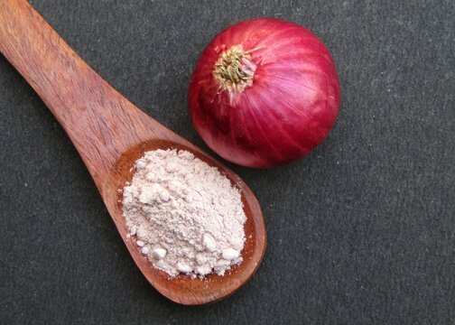Red Onion powder on a wooden spoon with onion top view 