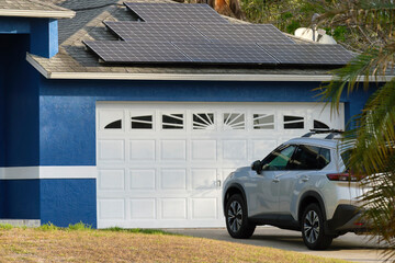 Car parked in front of wide garage double door on concrete driveway of new modern american house