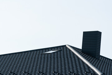 Fototapeta na wymiar Black roof of a new house. Roof covering with steel tiles. Black roof with a skylight and a chimney
