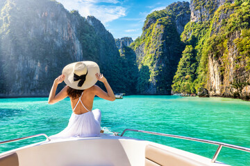 Elegant traveler woman in summer dress relaxing on boat at Maya beach, Phi Phi island, Tourism...