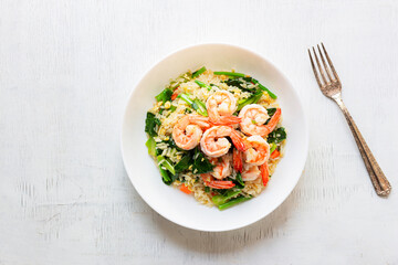 Fried rice with shrimp has vegetable in plate on white table.