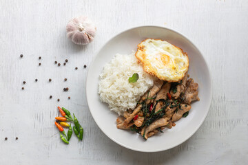 Stir fried basil with pork and fried egg has rice on white table top view.