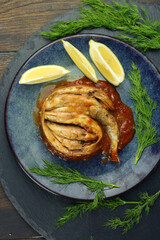 sprat fish in tomato sauce on the plate with lemon slices and dill closeup photo