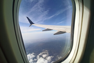 View through airplane window of commercial jet plane wing flying high in the sky. Air travelling...