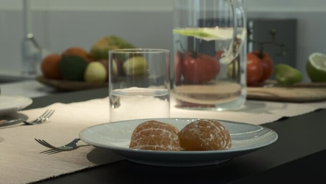 Frutas y agua en una jarra en una barra de cocina blanca y moderna. Mandarinas y manzanas