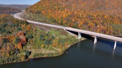 Cars and trucks traveling on highway crossing bridge over Tioga Reservoir in Autumn with Fall Colors