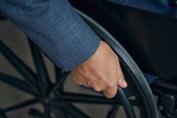 Close up shot of male hand on the wheel of wheelchair