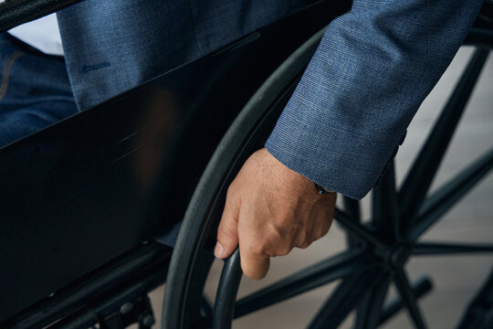Close-up photo of male hand on the wheel of wheelchair