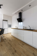 Modern interior of kitchen, wooden furnitureand stylish table and chairs. Spacious and luxurious space in apartment.
